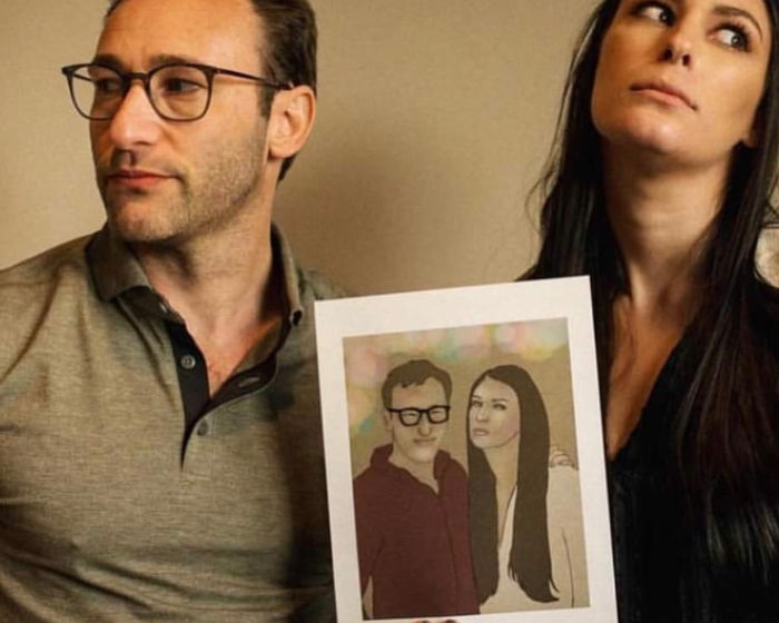 Two people holding an illustrated portrait